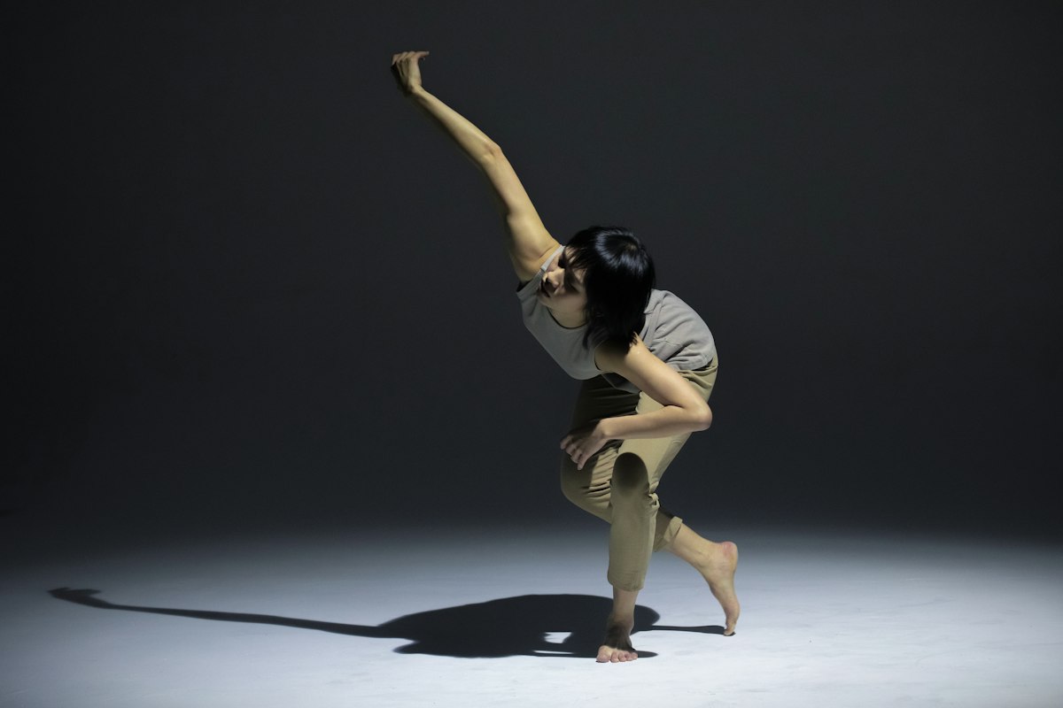 スポットライトの下で体を大きく反らせて踊るダンサー