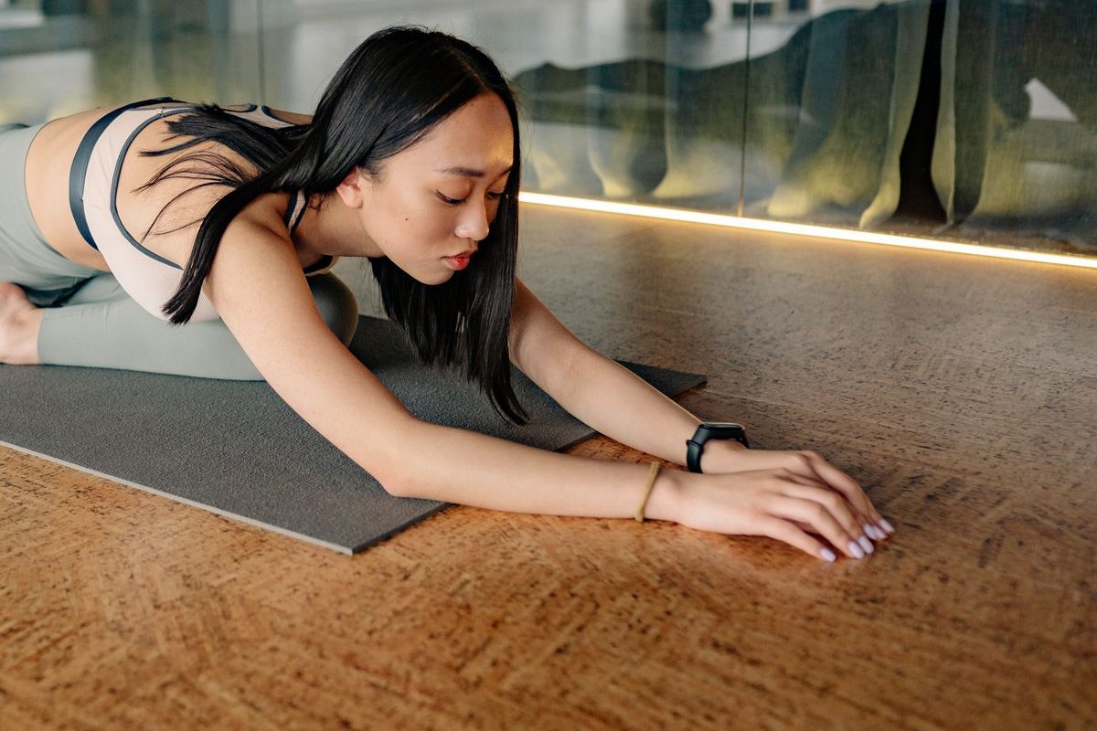 スタジオのマットの上でストレッチをする女性